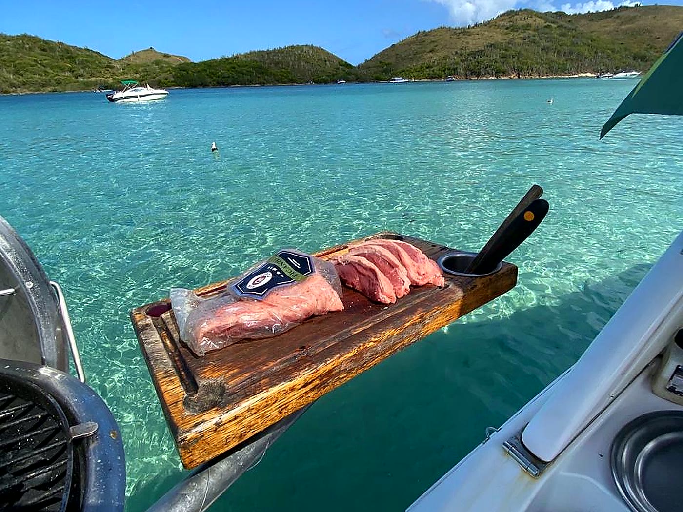 Carnes prontas para o churrasco na popa, em água cristalina